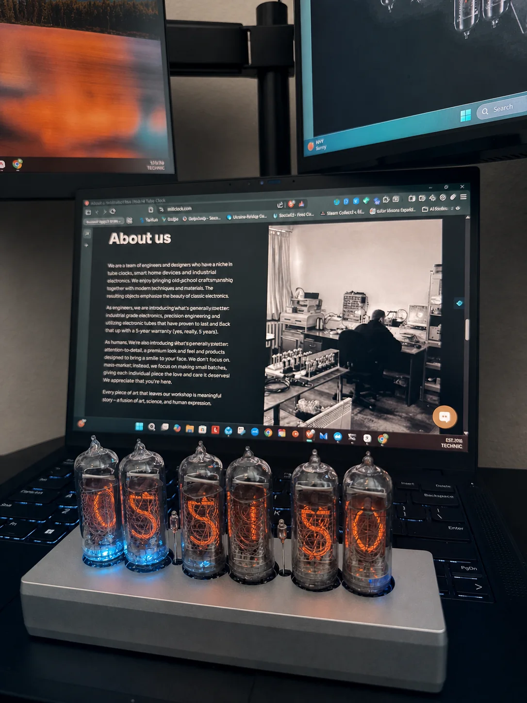 Six-tube Millclock IN-14 clock glowing in front of a laptop displaying the Millclock workshop story